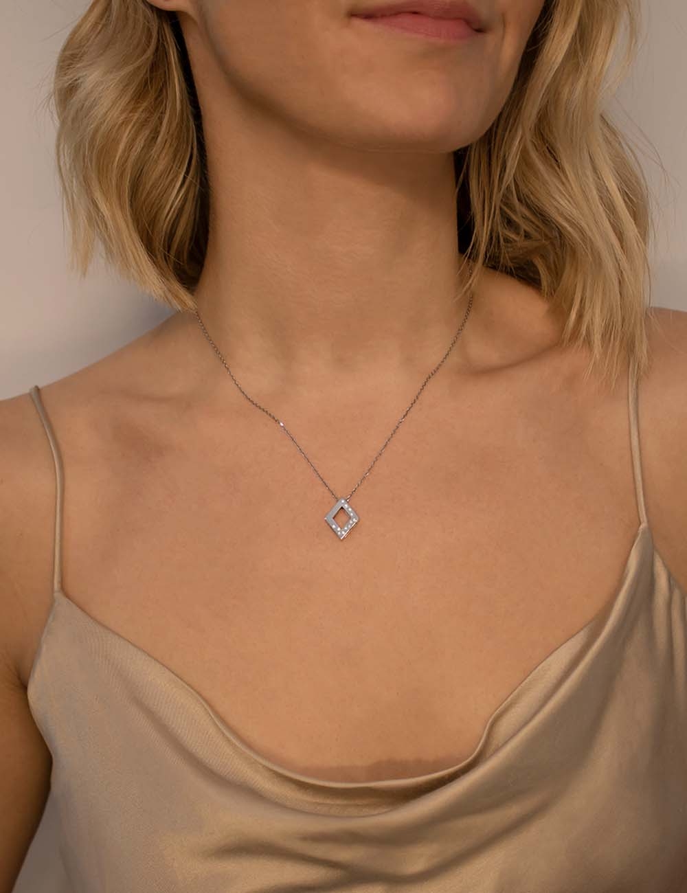 A women's pendant in a diamond shape, made of gold and adorned with white diamonds, suitable for everyday wear.