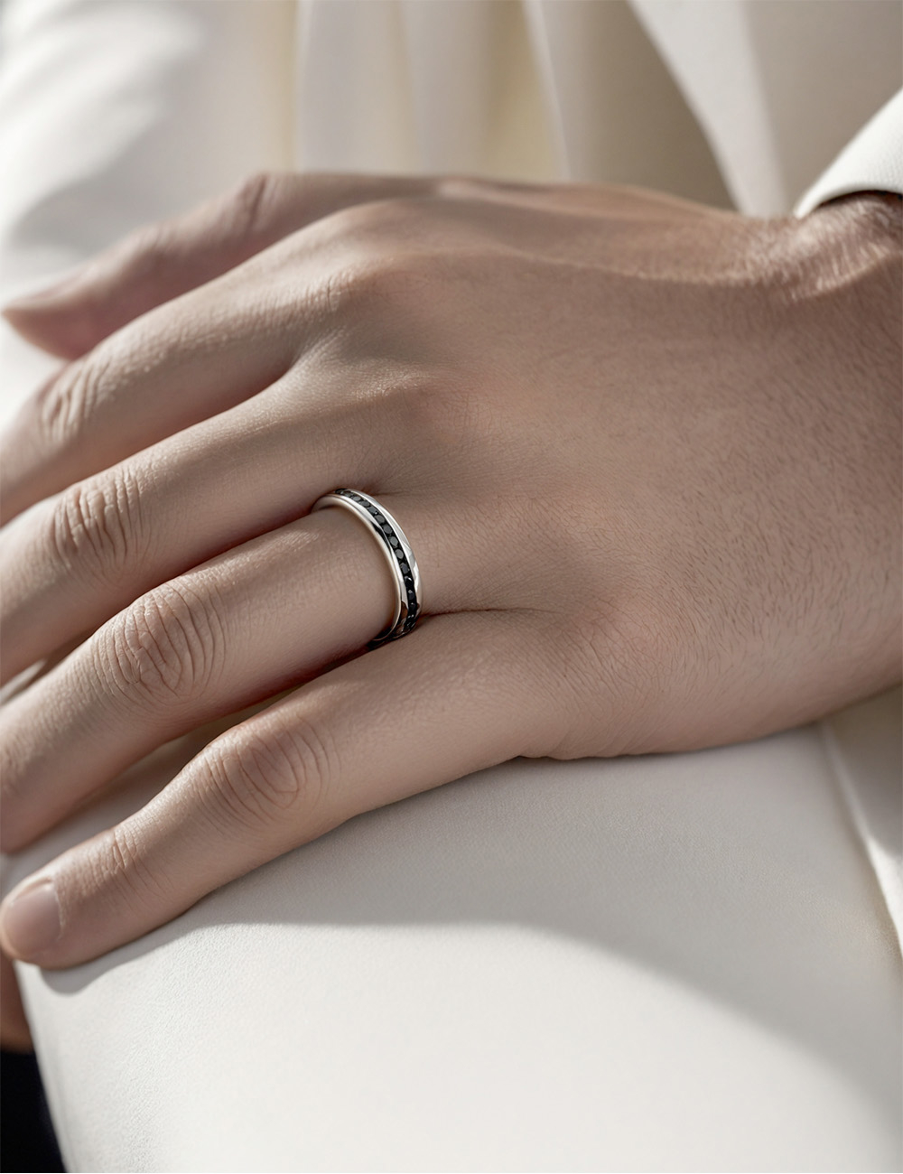 Alliance jonc homme en platine avec diamants noirs, portée à la main, photo élégante en lumière naturelle.