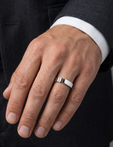 Bague homme en platine sertie de diamants blancs et noirs, portée à l’annulaire.