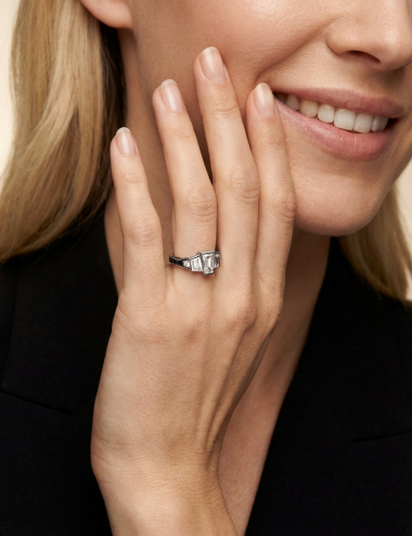 Close-up of the L’Origine ring worn, featuring three natural step-cut diamonds and a black diamond-set band.