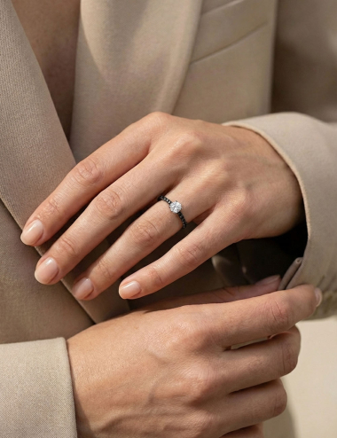 Bague solitaire en platine portée, diamant rond et diamants noirs latéraux, style élégant contemporain.
