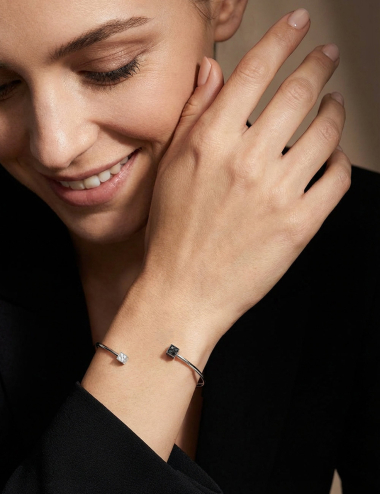 Open white gold bangle bracelet set with a white diamond cube and a black diamond cube.