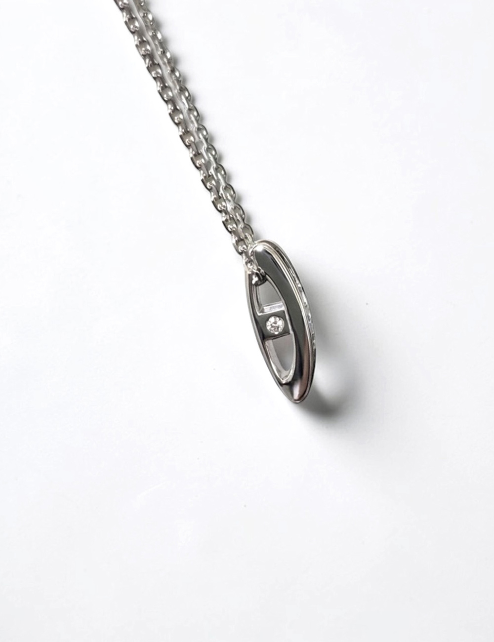 Collier en or blanc avec pendentif serti de trois diamants blancs naturels et de diamants noirs.