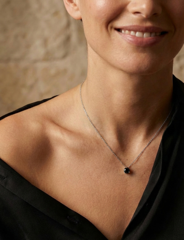 D.Bachet 1-carat black diamond solitaire pendant in white gold, worn by a woman on a black shirt. Modern luxury style.