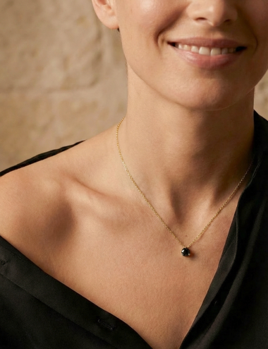 Pendentif solitaire diamant noir 1 carat D.Bachet or jaune, porté par une femme sur chemise noire. Style moderne.