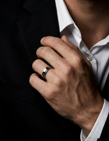 Men’s platinum wedding band with a slightly offset line of black diamonds, structured design, worn.