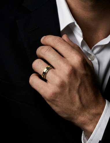 Men’s yellow gold wedding band with an offset line of black diamonds, structured design, worn.