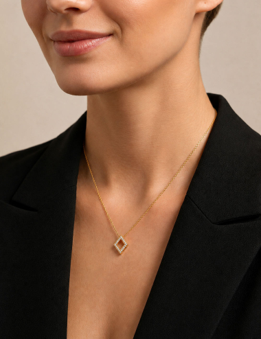 Openwork diamond-shaped pendant in yellow gold and white diamonds worn by a woman with a black blazer.