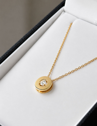 Pendentif cercle ajouré en or jaune pour femme avec un diamant central, présenté dans son écrin de joaillerie.