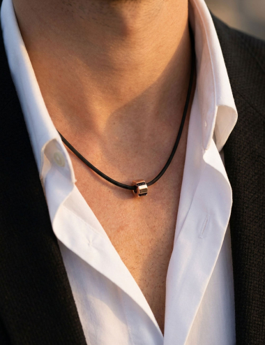 Pendentif D.Bachet or jaune et diamants noirs porté au cou d'un homme sur cordon noir.
