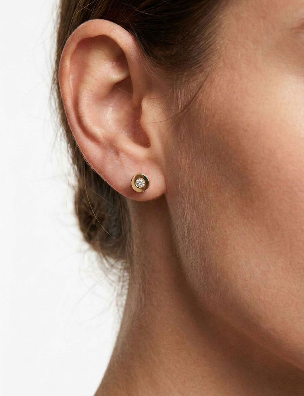 Gros plan sur le mannequin portant la boucle d'oreille cylindrique ajourée en or jaune et diamant Aura.