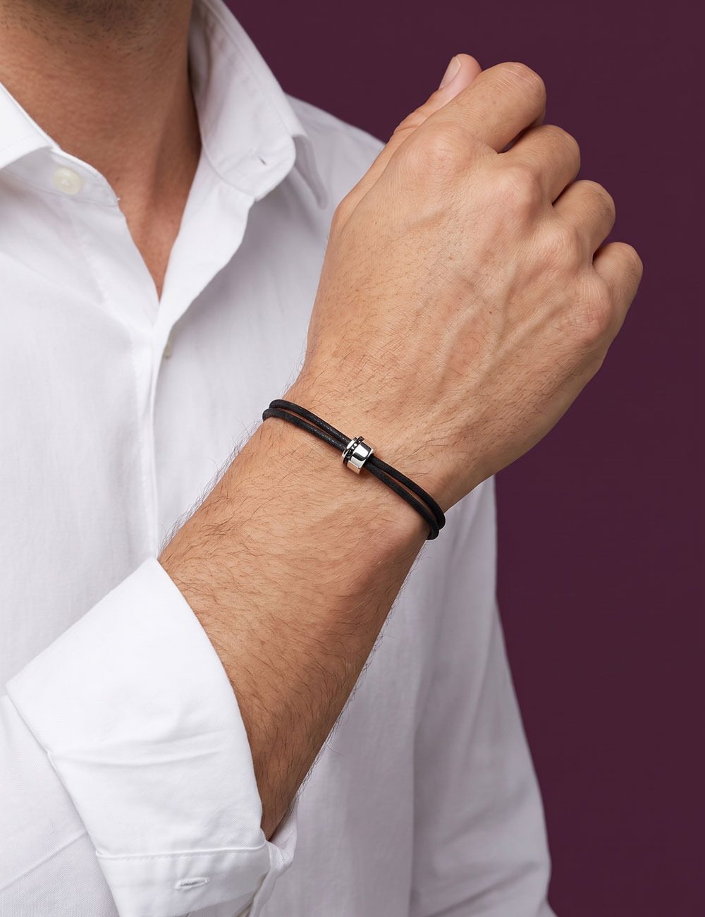 Man wearing the Sweet Side of Love bracelet in 18k white gold with channel-set black diamonds and a black cotton cord.