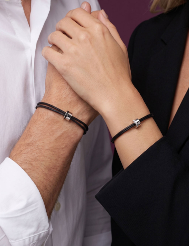 Couple wearing Sweet Side of Love black cord bracelets in white gold, with white diamonds for her and black diamonds for him.