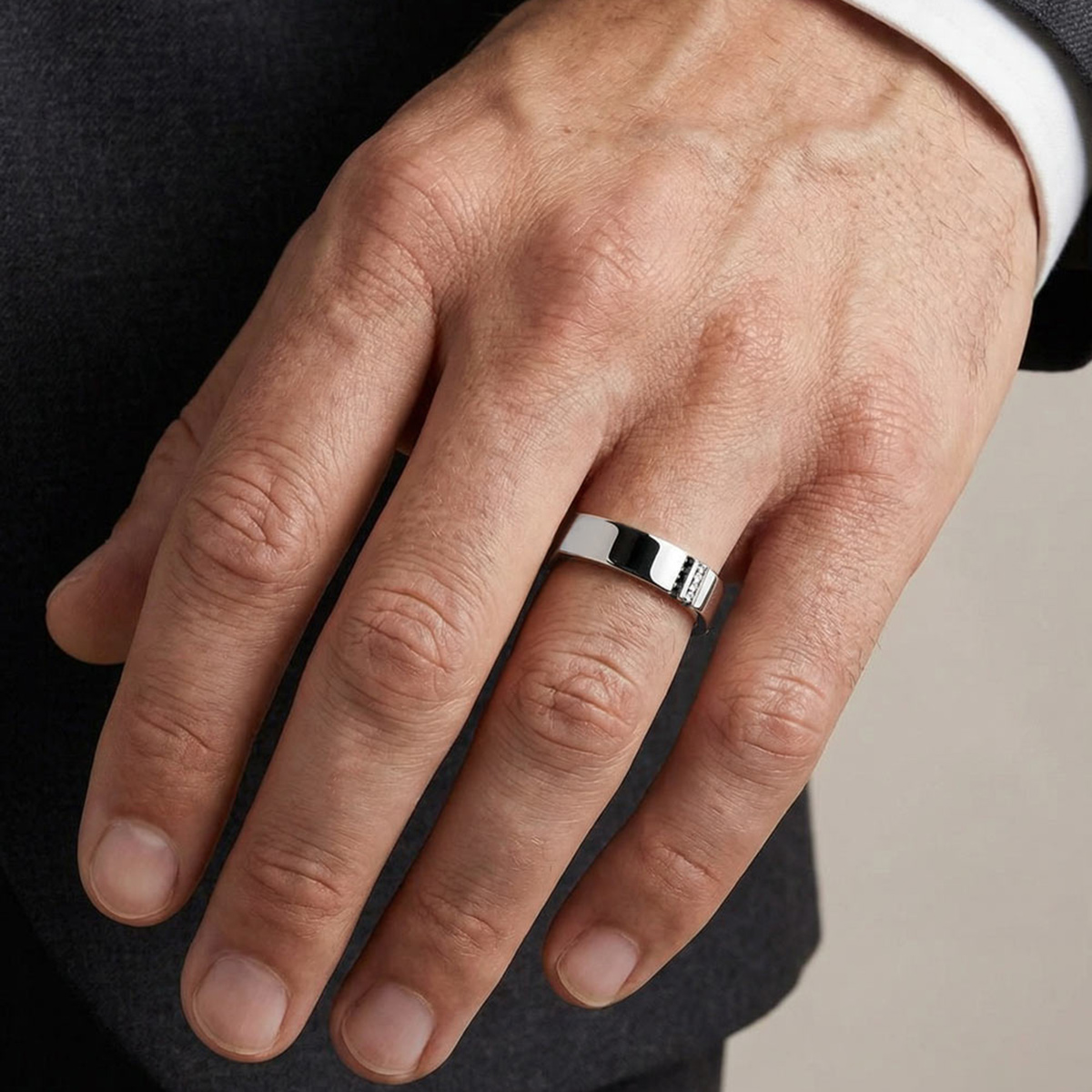 Bague de fiançailles homme en platine avec diamants blancs et noirs portée à l’annulaire sur une main, design D.Bachet.