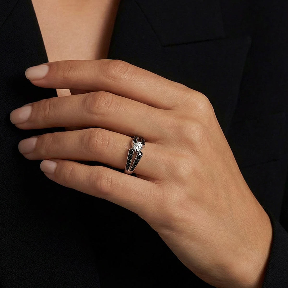 Bague de fiançailles en platine avec diamant blanc central et diamants noirs sur le corps de bague portée sur la main