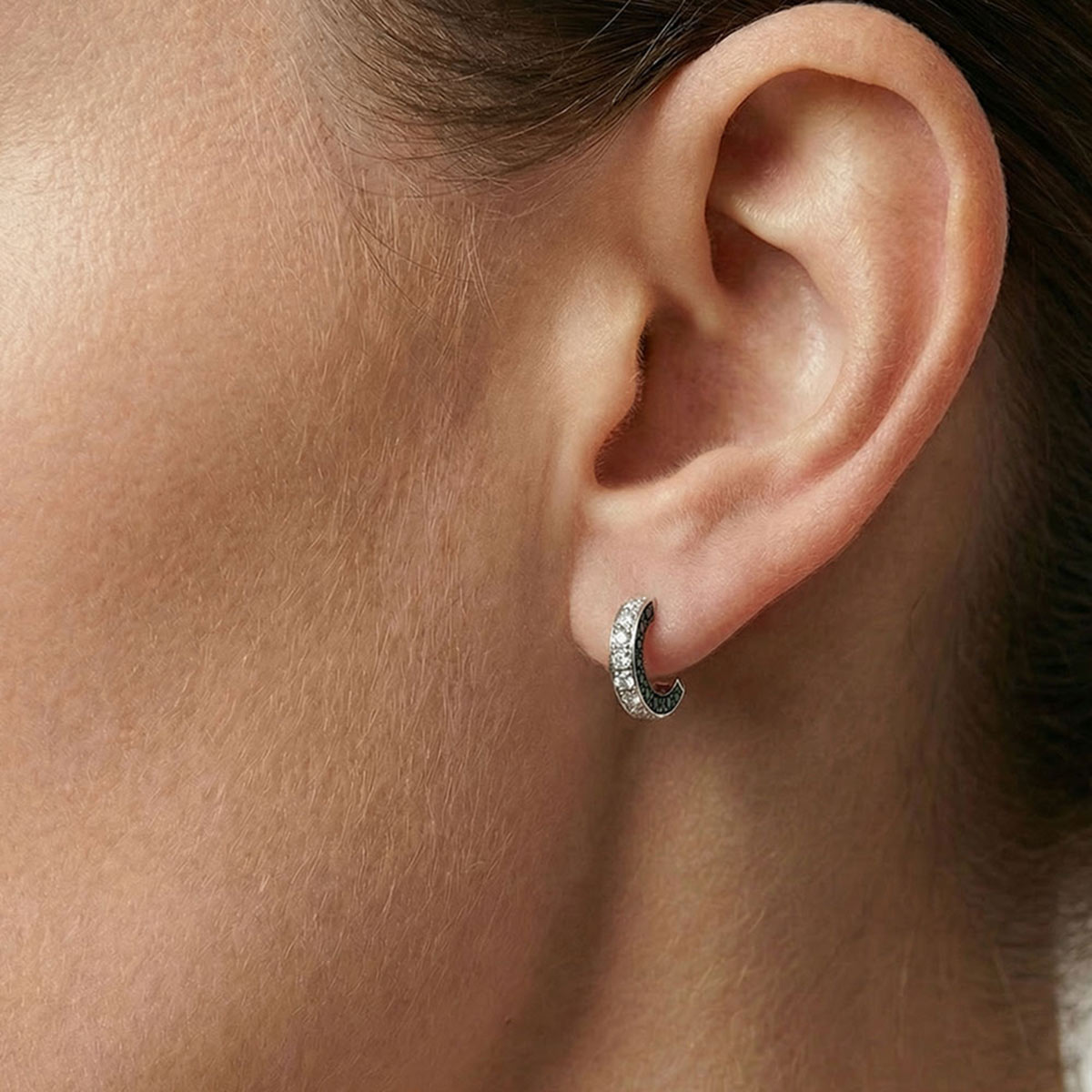 Boucles d'oreilles femme en or blanc 18 carats, damants blancs et noirs, portées par une femme.