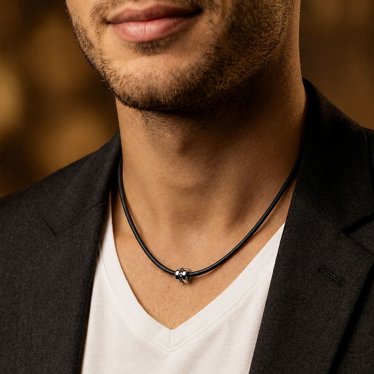 Pendentif homme en or blanc et diamants noirs, sur cordon en silicone noir, porté par un homme.